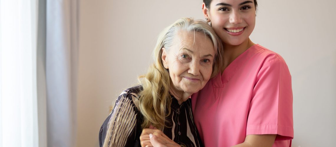 Happy caregiver and senior patient smiling and looking at camera