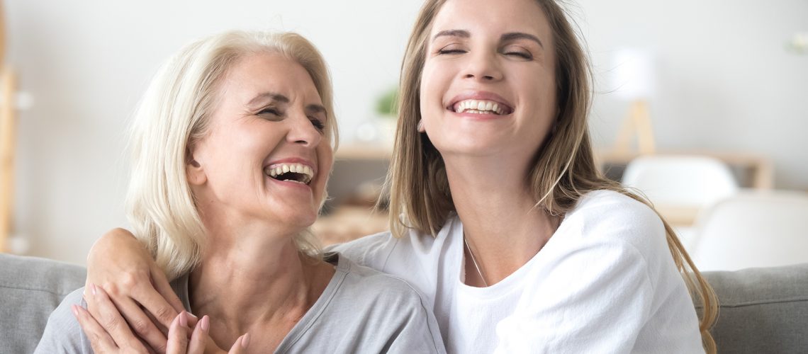 Happy senior mature mother embracing young adult woman laughing